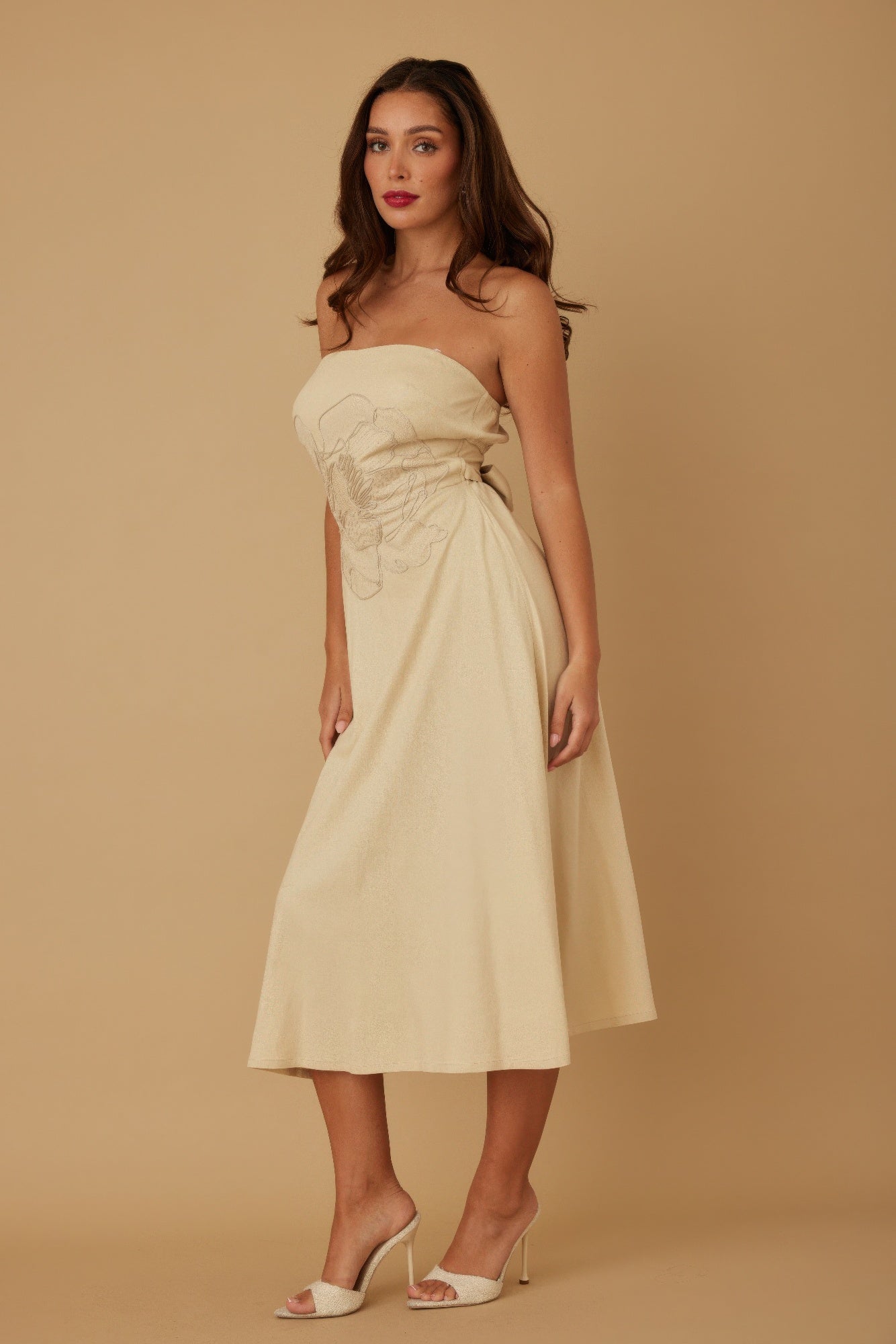 Side angle of beige strapless midi dress showing flowy skirt and fitted bodice
