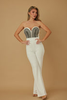 Woman wearing a black and ivory strapless embroidered bodice jumpsuit with wide leg pants
