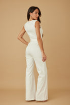 Back three quarter view of white wide leg jumpsuit showing tailored trouser and tie waist, AVAH