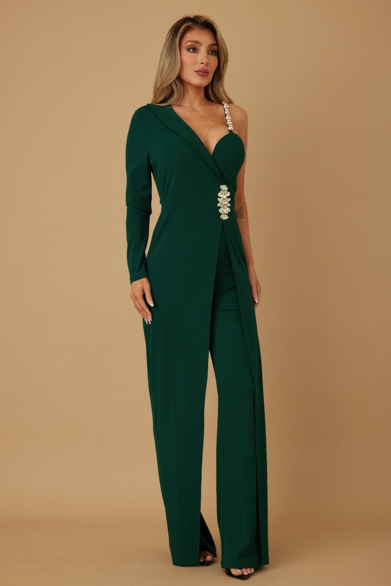 Side view of emerald one-shoulder jumpsuit highlighting crystal strap detail
