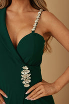 Close-up of crystal-embellished shoulder strap and waist detail on emerald jumpsuit
