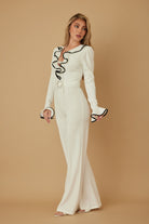 Side view of ivory ruffle trim jumpsuit with flared cuffs
