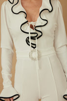 Close-up of ruffle neckline and tie detail on ivory jumpsuit
