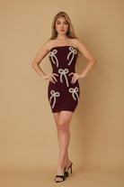 Burgundy strapless mini dress with pearl and stud bow embellishments, front view on model.