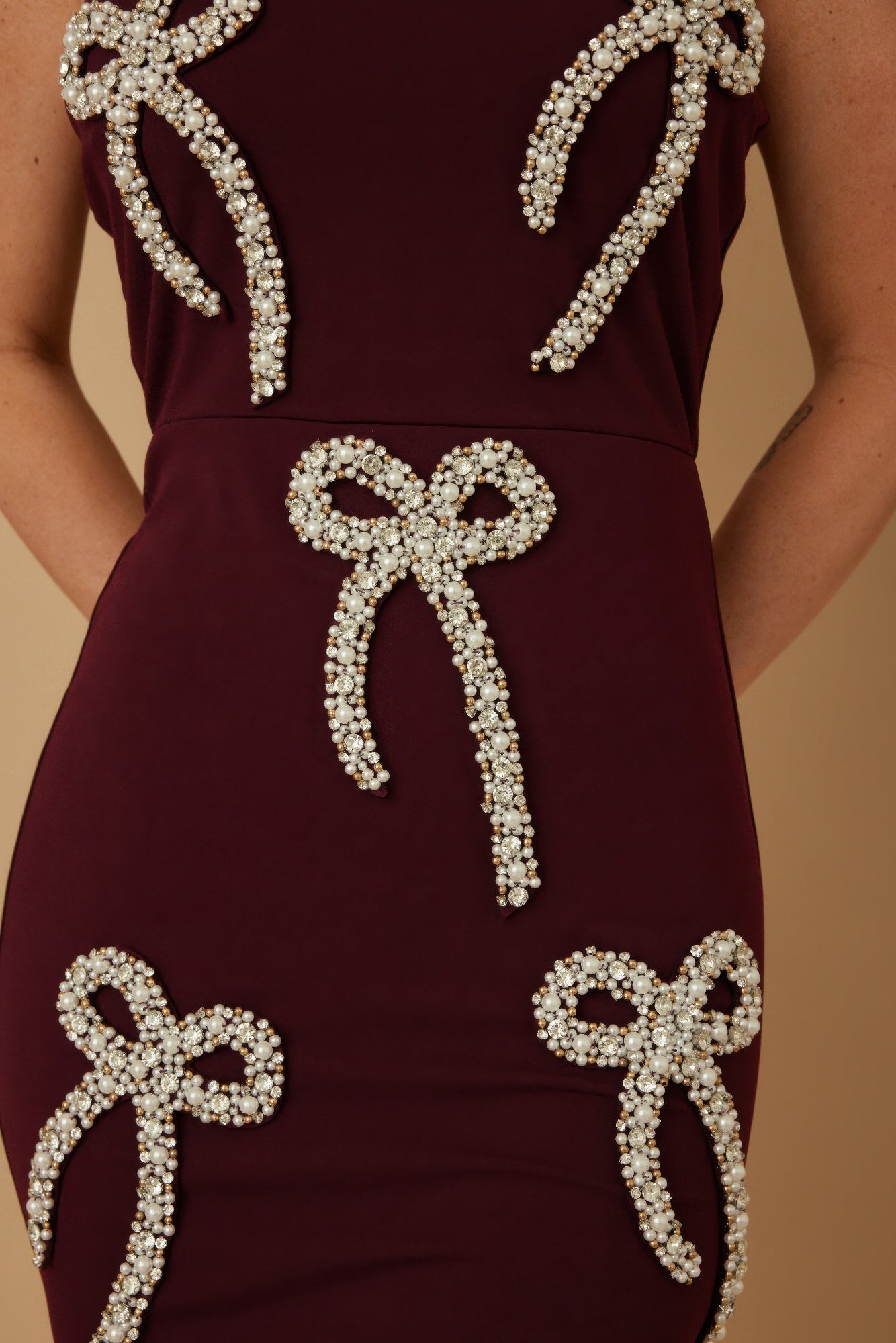 Burgundy strapless bow-embellished mini dress, close-up of pearl and stud bows.