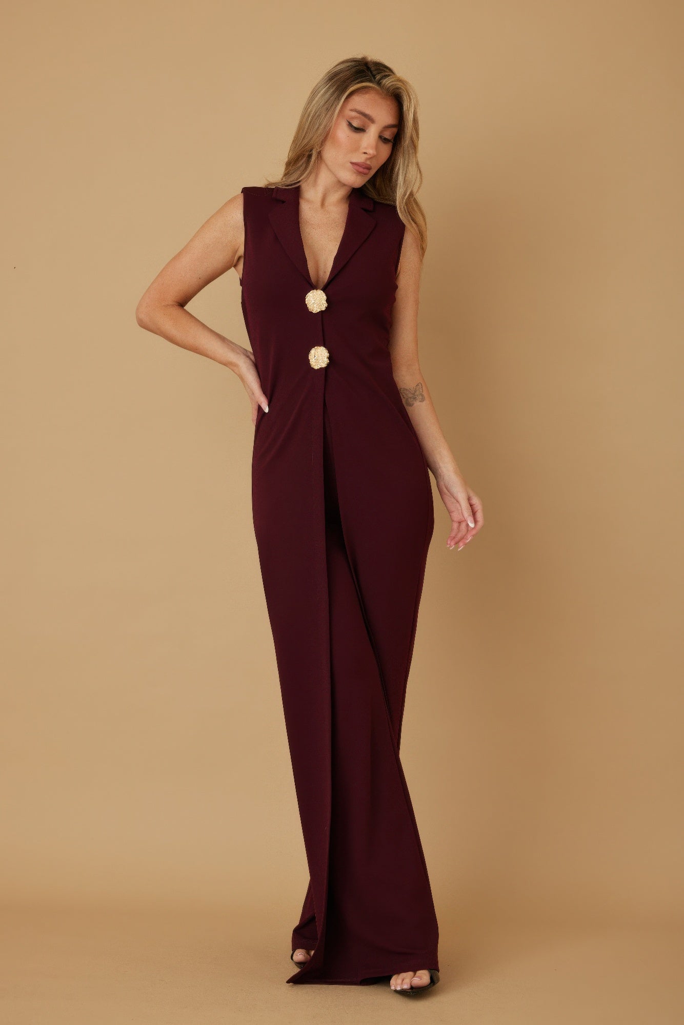 Full length front view of burgundy sleeveless lapel jumpsuit with decorative gold buttons, AVAH