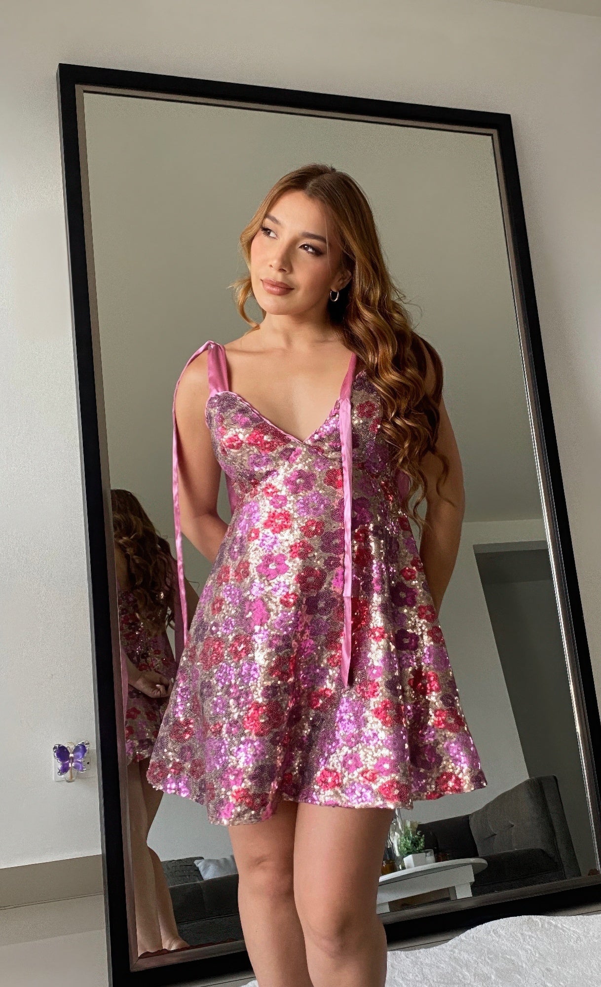 Close-up of woman in pink floral sequin mini dress, showing V-neckline and satin straps.