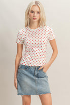 Model wearing white fitted polka dot tee with red dots and denim mini skirt
