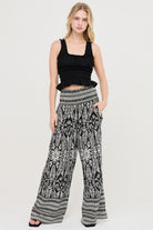 Model wearing a black top and floral wide leg pants 