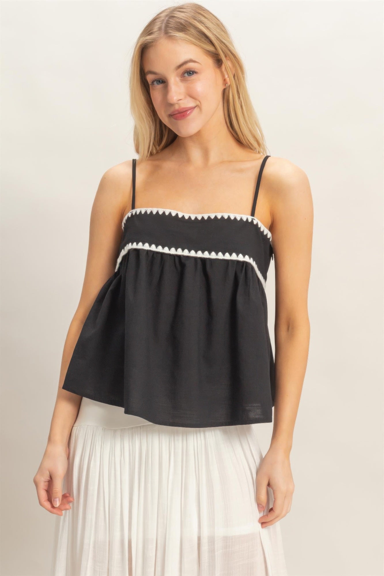 Model wearing black embroidered babydoll cami top with white maxi skirt
