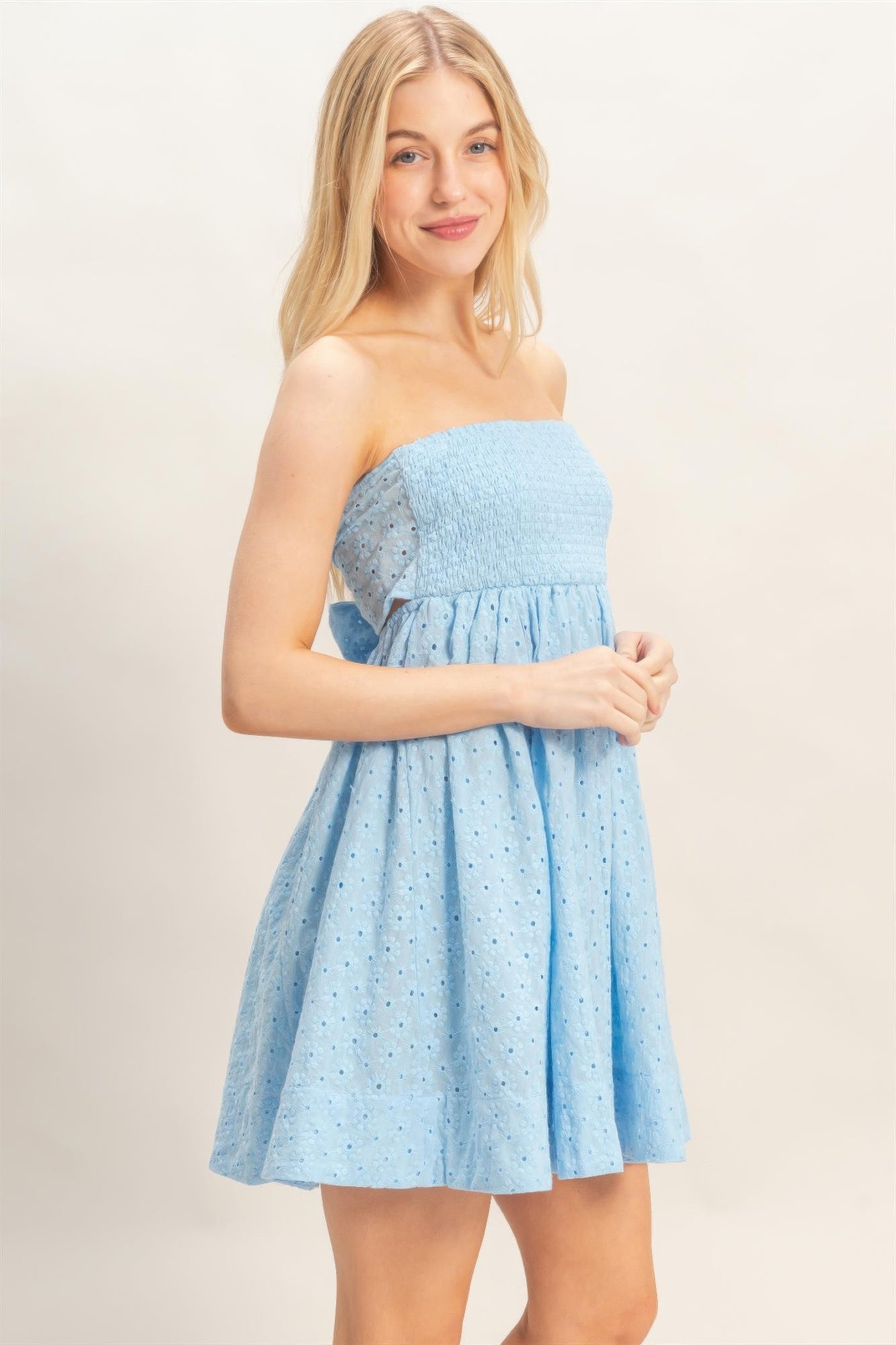 Side view of blue smocked strapless mini dress with flowy skirt
