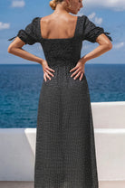 Three quarter back view of the Cala Luna Puff Sleeve Midi Dress in black polka dot featuring the smocked back and adjustable sleeve ties.