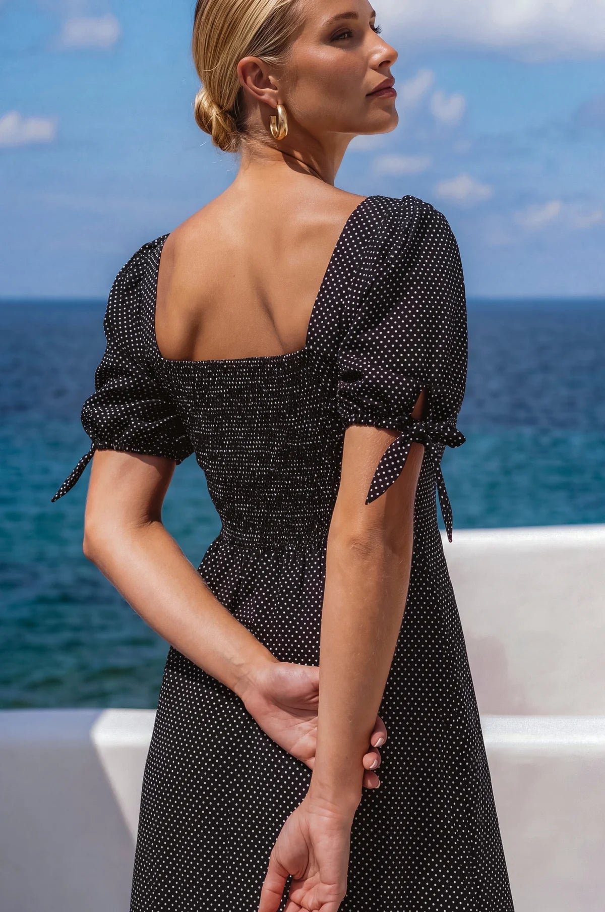 Back view of the Cala Luna Puff Sleeve Midi Dress in black polka dot showcasing the smocked back, puff sleeves, and flowing midi skirt.