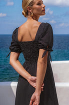 Back view of the Cala Luna Puff Sleeve Midi Dress in black polka dot showcasing the smocked back, puff sleeves, and flowing midi skirt.