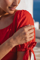 Close up of the Cala Luna Puff Sleeve Midi Dress in red highlighting the puff sleeve and adjustable tie detail.