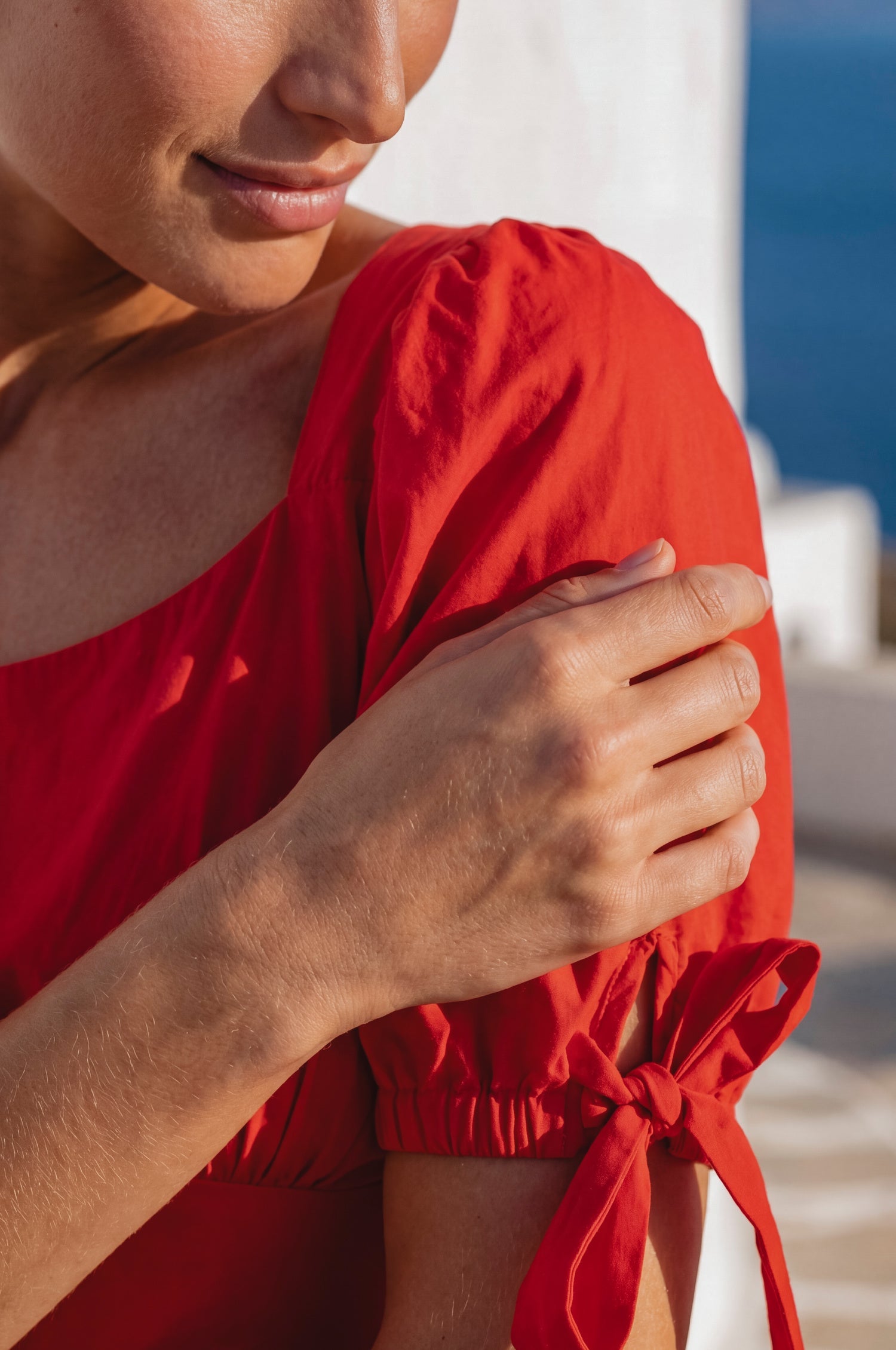 Close up of the Cala Luna Puff Sleeve Midi Dress in red highlighting the puff sleeve and adjustable tie detail.