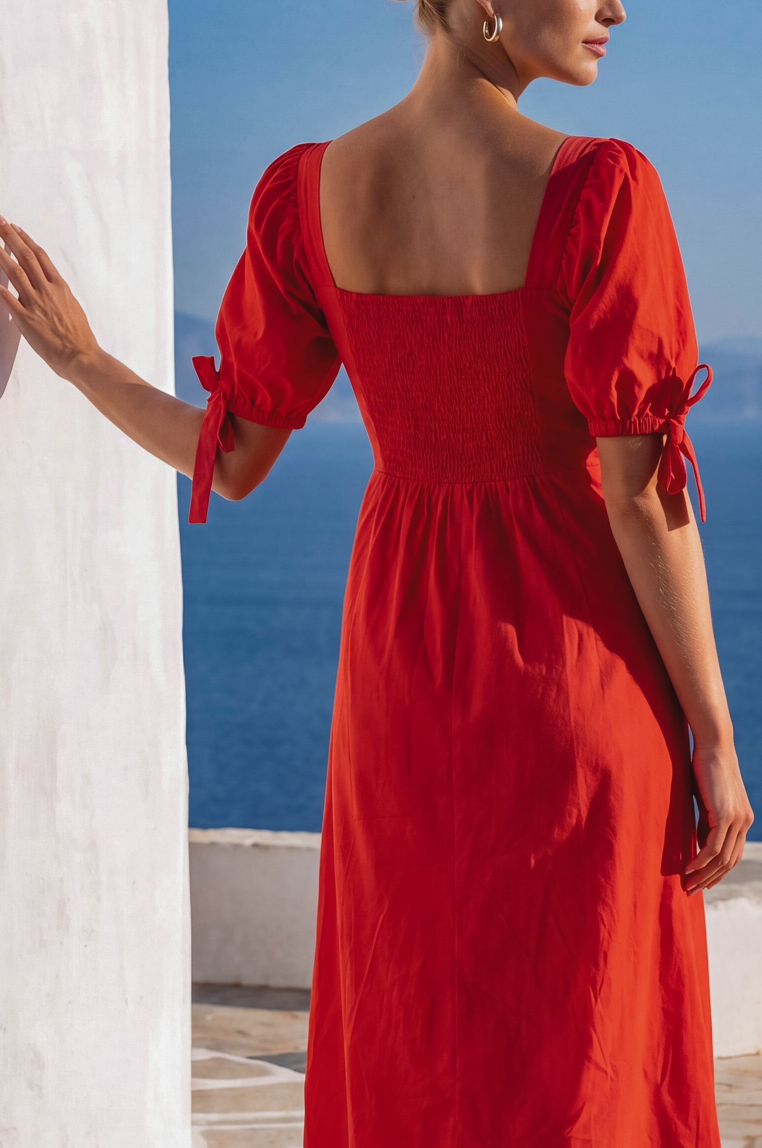 Back view of the Cala Luna Puff Sleeve Midi Dress in red showcasing the smocked back and puff sleeves with tie details.