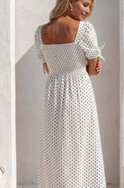 Back view of the Cala Luna Puff Sleeve Midi Dress in white polka dot featuring the smocked back and puff sleeves with tie details.