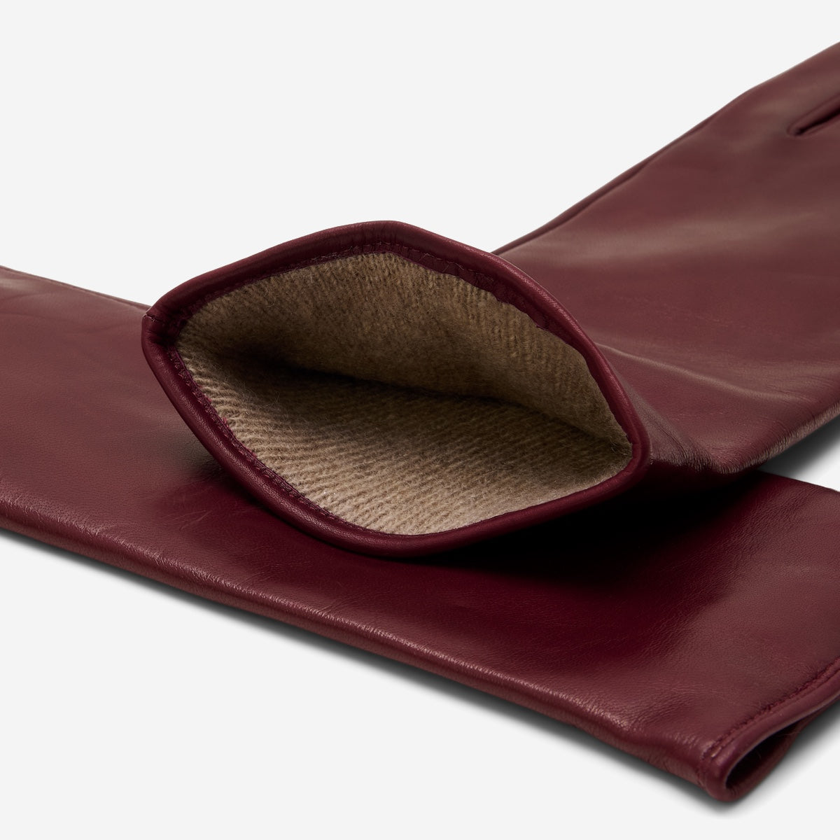 Close-up of a maroon leather glove with brown lining on a white background