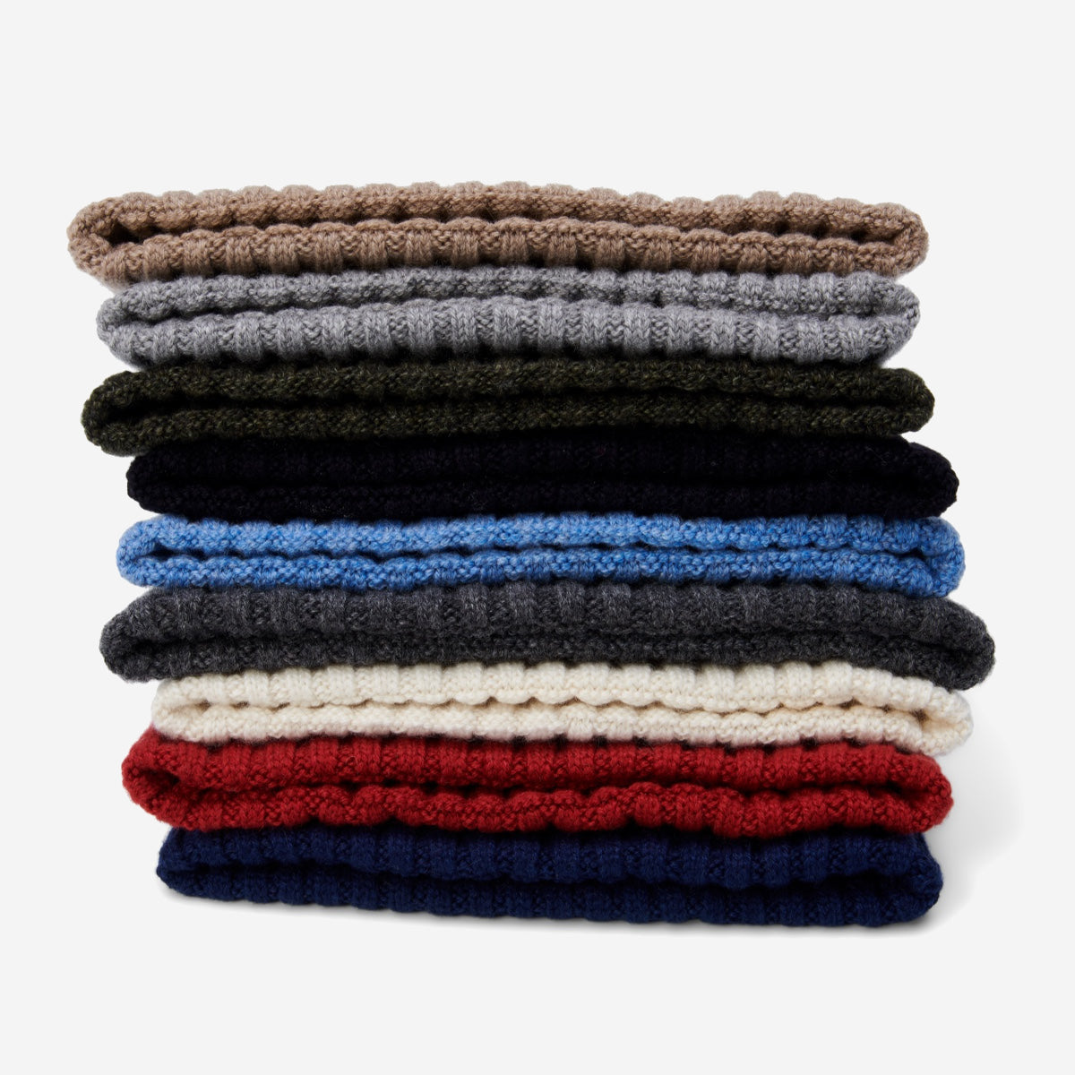 Stack of folded beanies in various colors on a white background