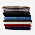 Stack of folded cashmere beanies in various colors on a white background