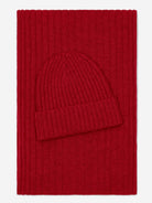 Red knit beanie and scarf set on a red background