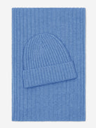 Blue knit beanie and scarf set on a matching blue fabric background