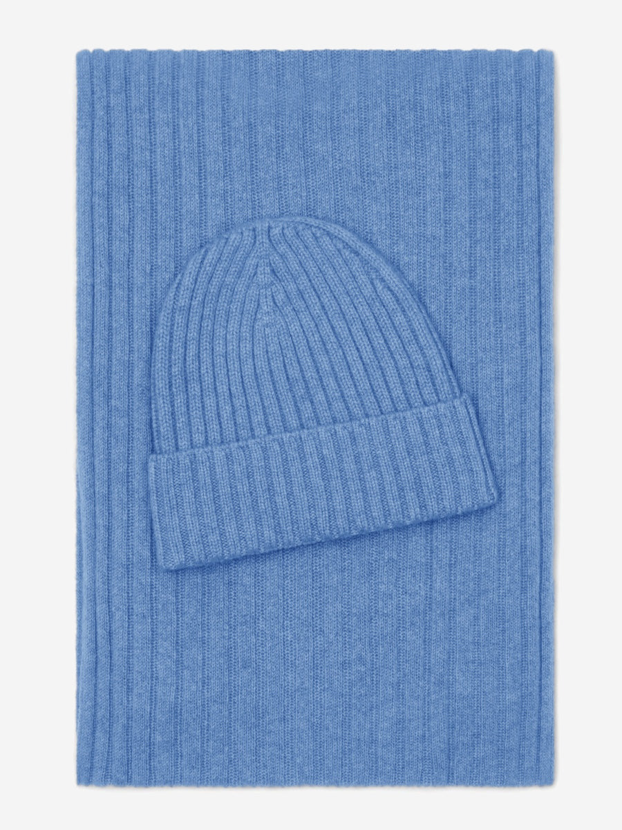 Blue knit beanie and scarf set on a matching blue fabric background