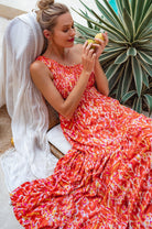 Woman in a colorful dress holding an apple outdoors with plants in the background