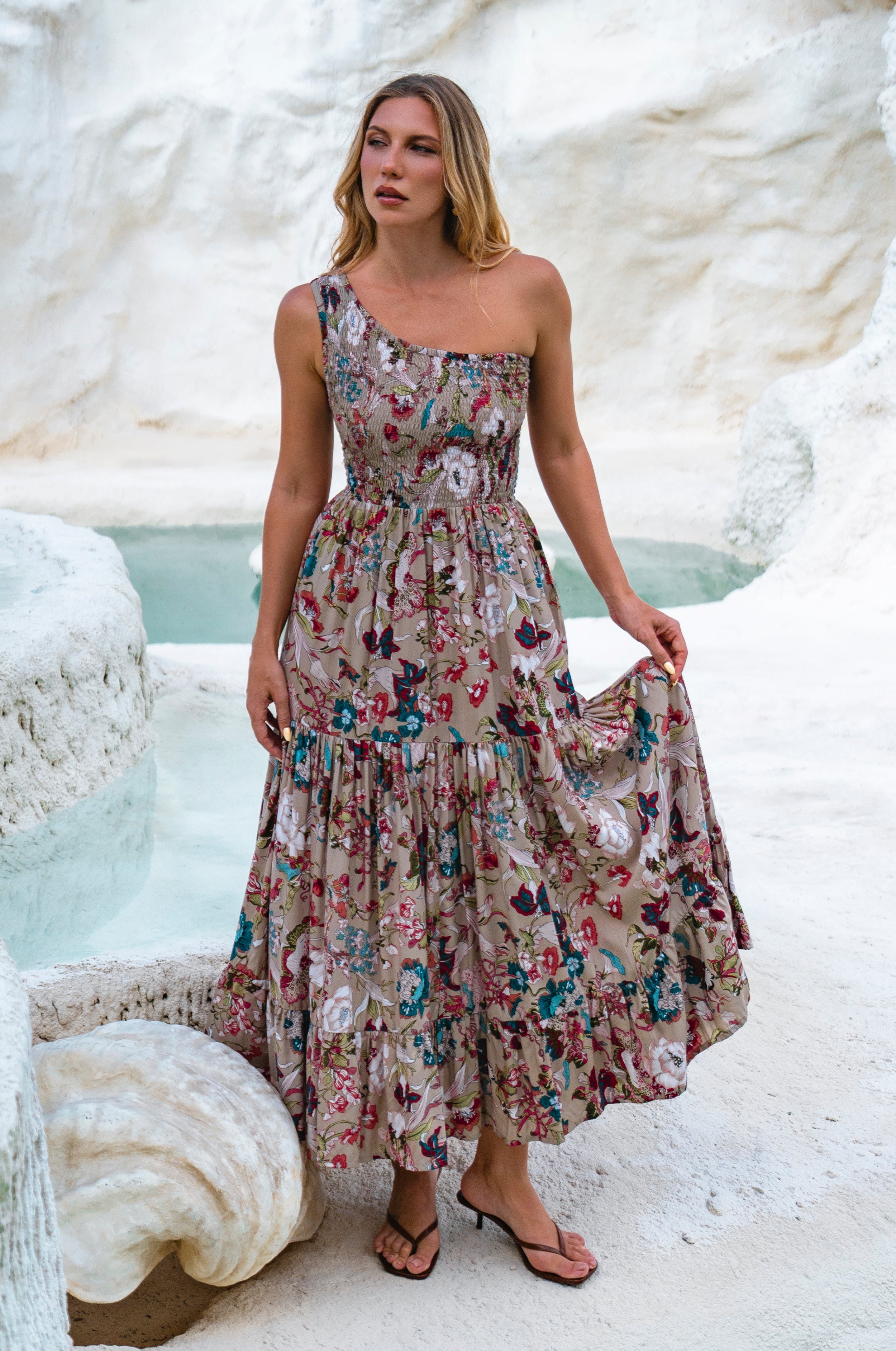 Woman in a gray floral one-shoulder maxi dress standing in a white landscape, front view