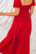Red dress with a smocked back design on a light background, back view closeup