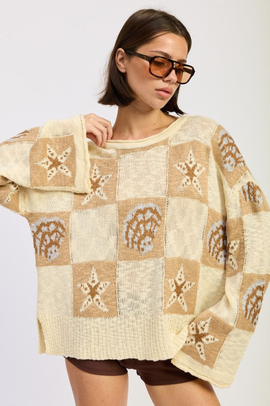 Woman wearing a cream and taupe patchwork knit sweater with star and seashell motifs, front view. and brown knee-high boots on a white background