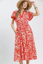 Model wearing a red and ivory floral midi dress with flutter sleeves, split neckline, elastic waist, side pockets, and a ruffle hem.