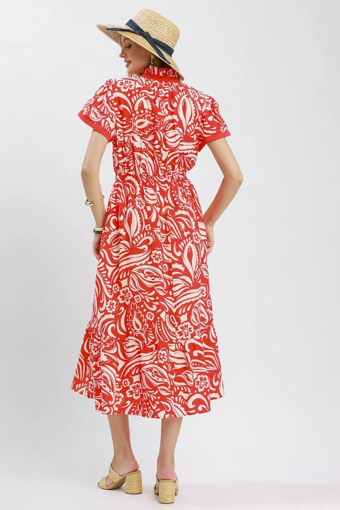 Model wearing a red and ivory floral midi dress with flutter sleeves, split neckline, elastic waist, side pockets, and a ruffle hem.