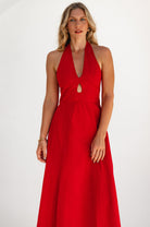 Woman wearing a red halter neck dress on a white background