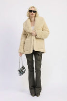 Model wearing a shearling teddy coat with oversized lapels and cozy texture
