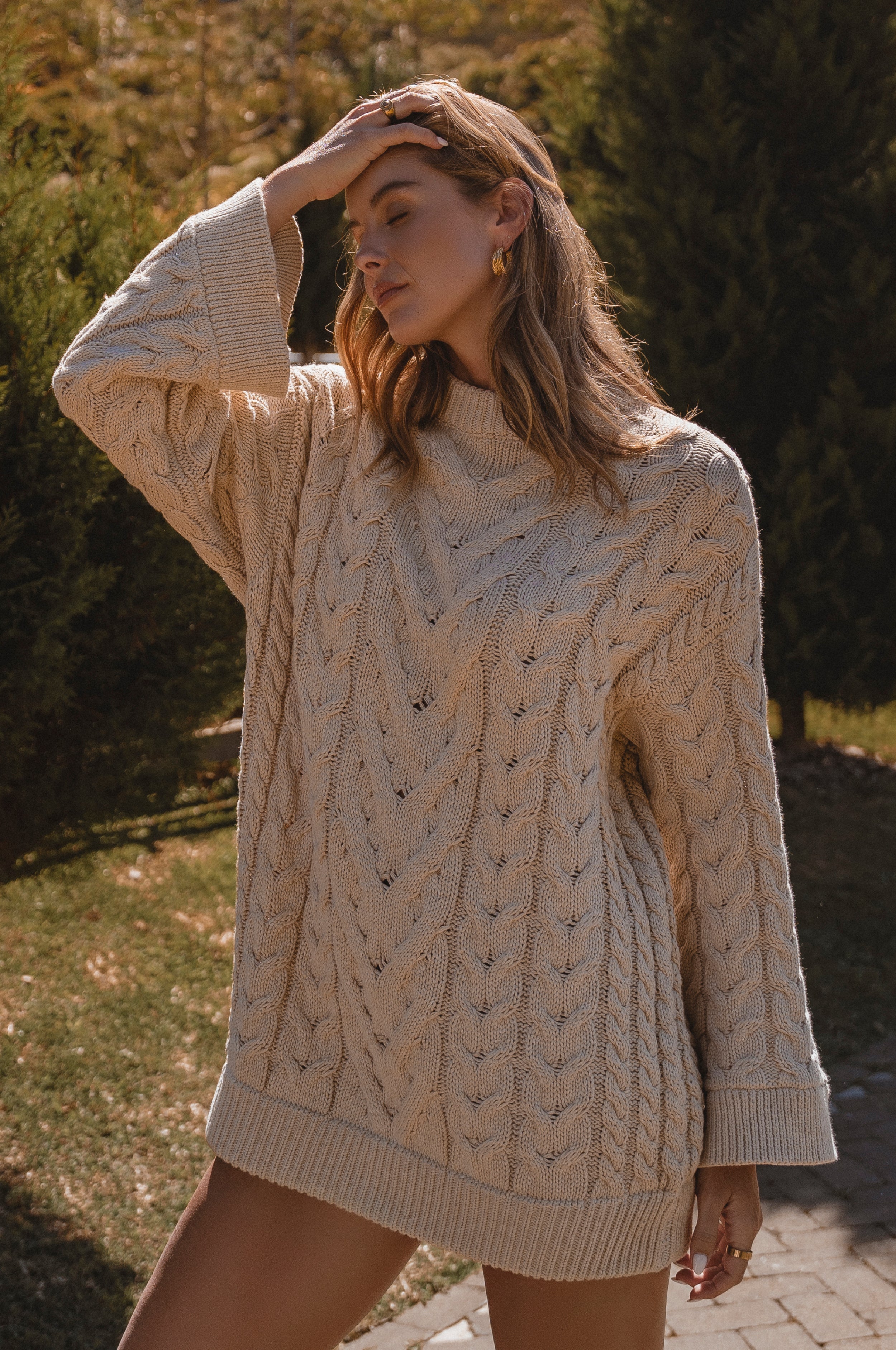 Woman wearing a beige cable knit sweater outdoors