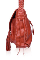 Close up of a red woven handbag with tassels on a white background, side view
