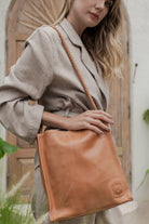 Woman holding a tan leather bag outdoors