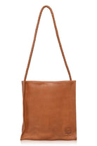 Tan leather tote bag with a strap on a white background