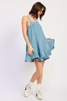 Woman wearing a light blue denim dress against a white background, front view