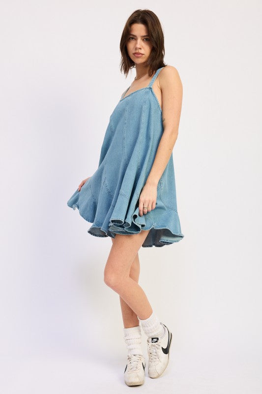 Woman wearing a light blue denim dress against a white background, side view