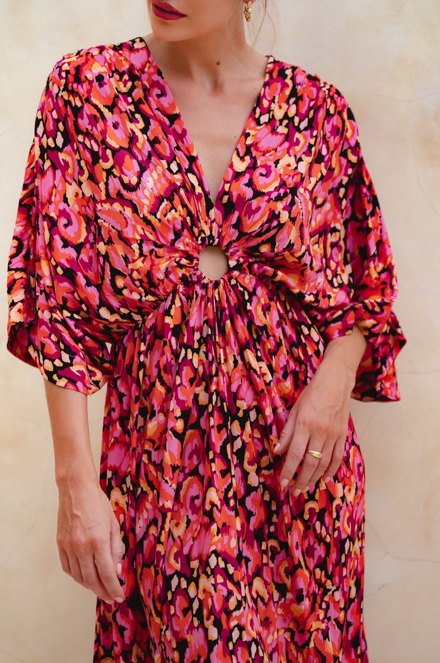 Woman wearing a vibrant, patterned dress with a neutral background, front view closeup