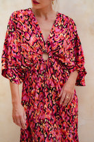 Woman wearing a vibrant, patterned dress with a neutral background, front view closeup