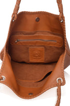 closeup of camel suede lined interior or camel leather handbag with visible brand logo on a white background