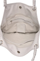Closeup of white suede lined interior of white leather handbag with multiple pockets and braided straps with silver toned hardware on a white background