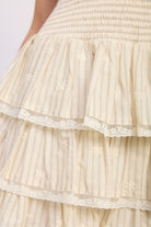 close up of woman wearing cream strapless smocked tiered mini dress front view on white background