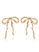 Gold-tone sculpted bow earrings with long wavy ribbon tails on white background.