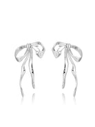 Angled view of silver-tone sculpted bow earrings on white background.