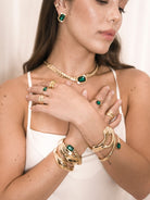 Woman styling green crystal wrap ring with matching necklace and earrings indoors.